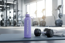 Charger l'image dans la galerie, Gourde fitness violette TrekkerSS posée sur tapis de gym avec haltères et salle de sport en arrière-plan
