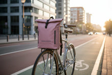 Charger l'image dans la galerie, Sac à dos rose TREKKERSS fixé sur un vélo stationné en ville au coucher du soleil
